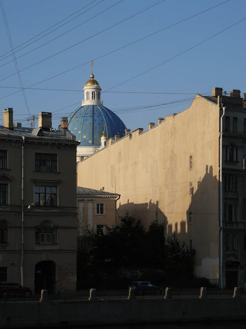 Photo of Concrete Buildings and Dome of a Church Under Blue Sky