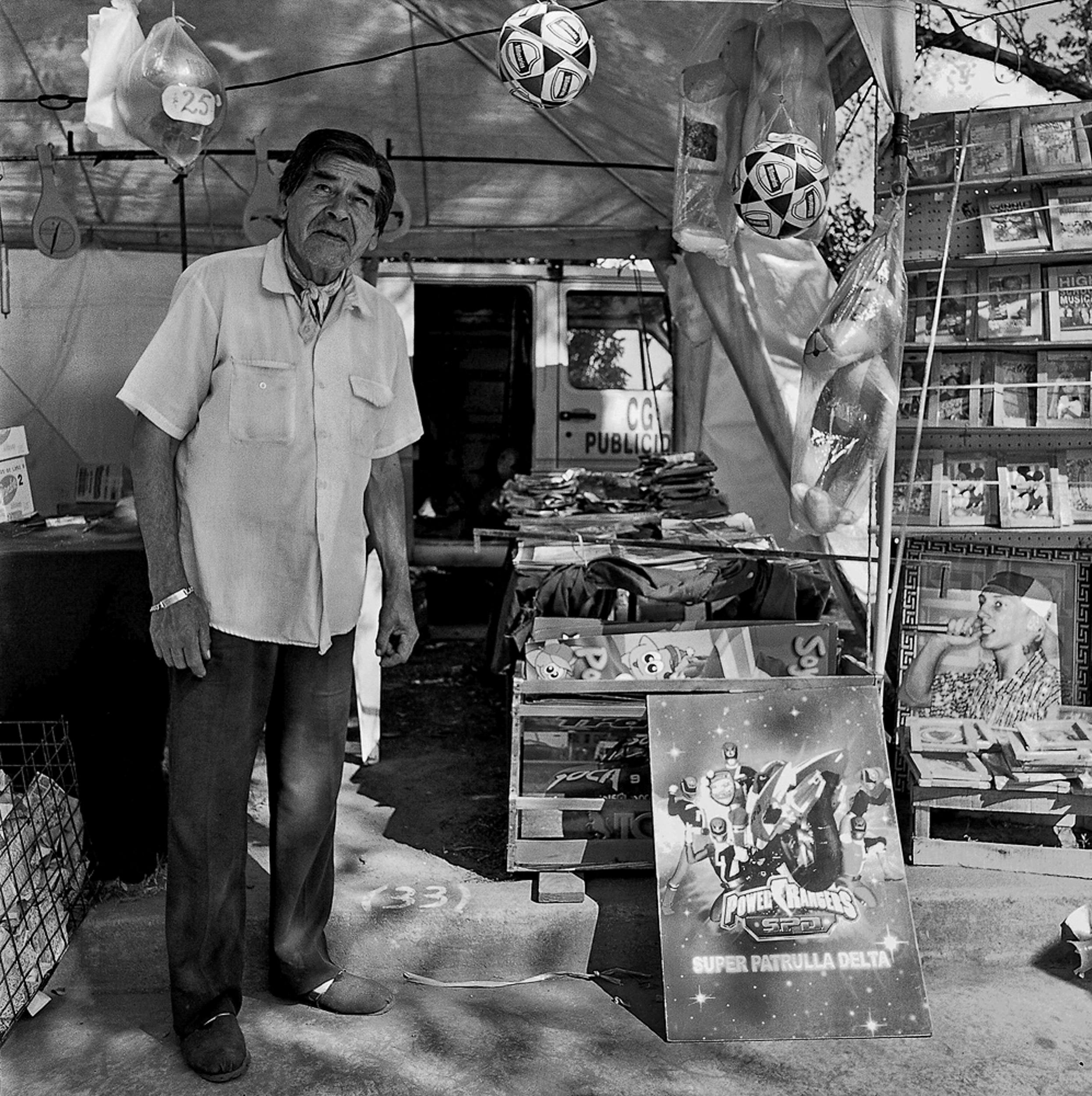 elderly man selling souvenirs on a street in black and white