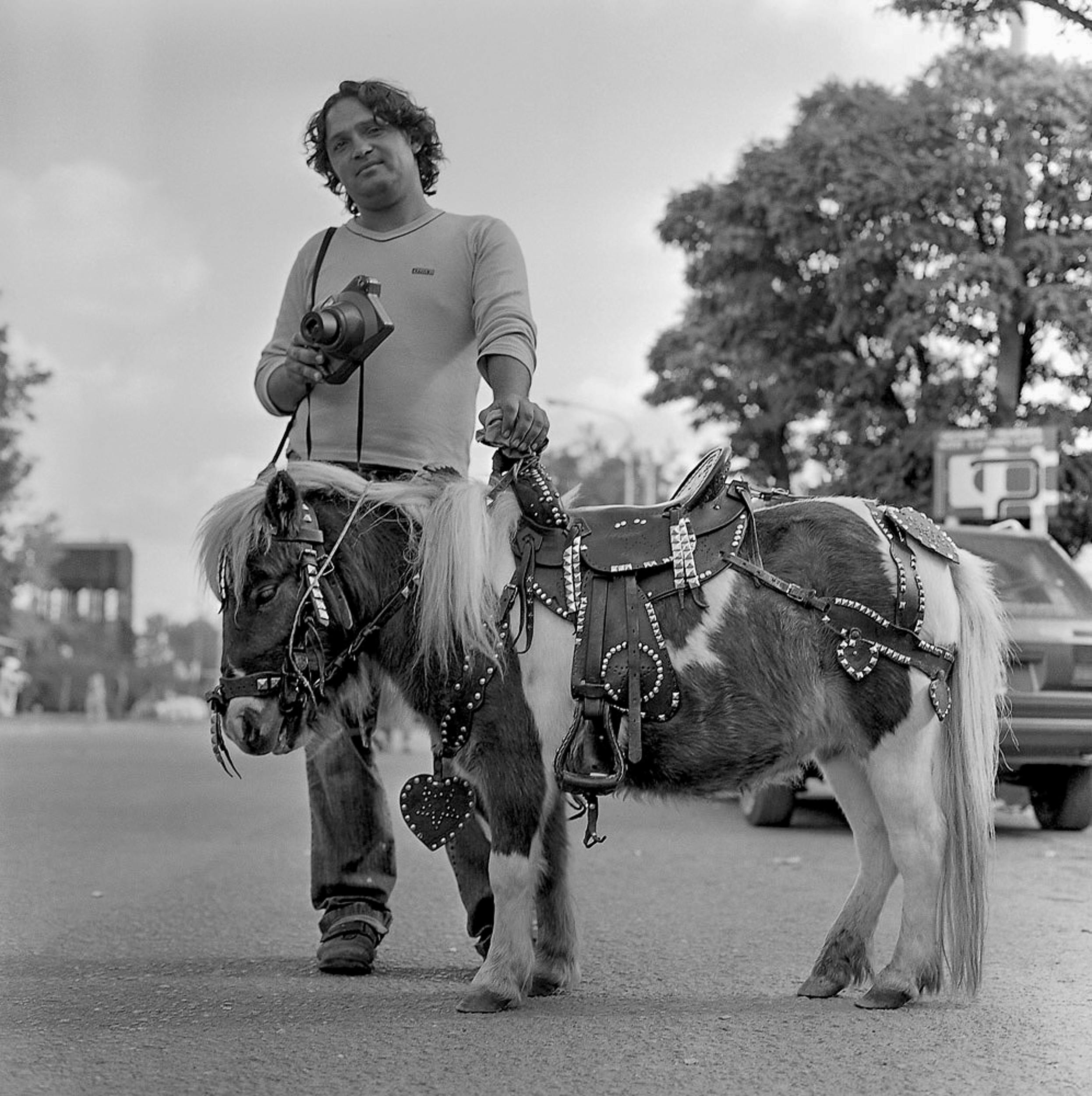 A striking black and white street photo of a man holding a pony in Ayacucho, Argentina.