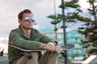 一位戴着太阳镜的休闲男子坐在滑板公园里，边反思边放松