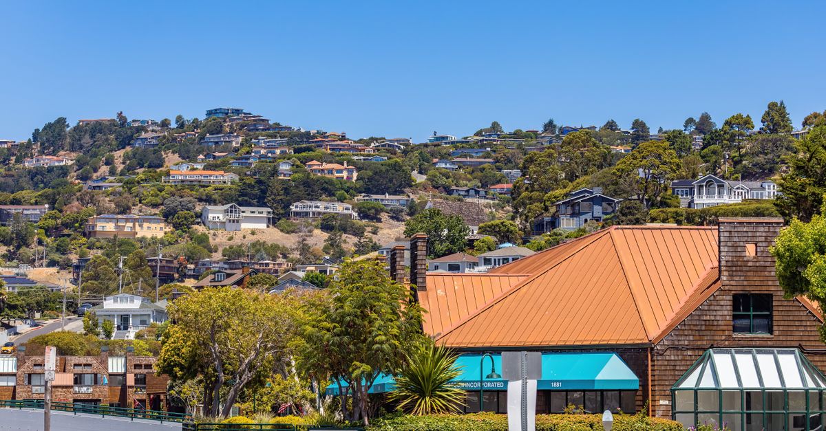 Picturesque hillside neighborhood with residential houses and lush greenery under a clear blue sky.