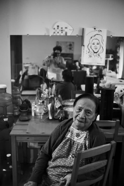 Grayscale Photo of an Elderly Woman Sitting on a Chair