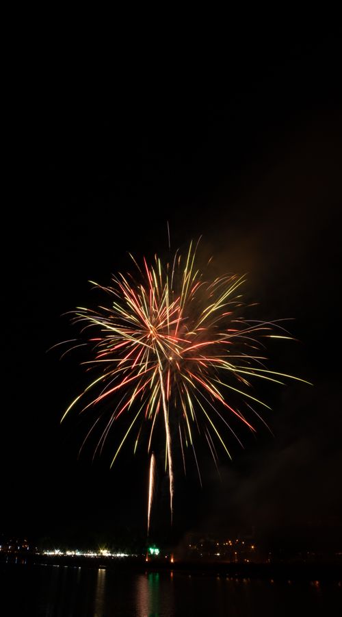 Free Colorful fireworks illuminate the night sky over a waterfront, celebrating an event. Stock Photo