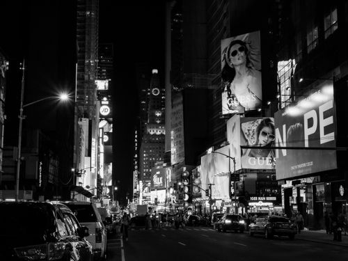 Free Monochrome view of Times Square's vibrant city lights and bustling street life at night. Stock Photo