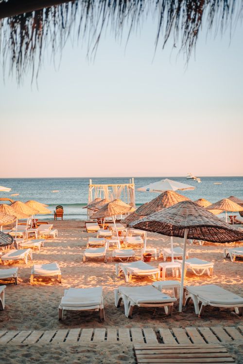 Free Relaxing beach scene with empty sunbeds and parasols at sunset, perfect for summer vacation imagery. Stock Photo