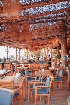 Charming outdoor dining area with wooden tables and chairs under rustic thatched roof.