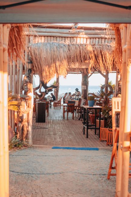 Rustic tropical restaurant with ocean views, warm lighting, straw roofing, and lively atmosphere at sunset. - A Foodies Guide to Holetown: Best Restaurants and Bars