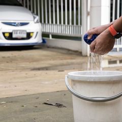 A white bucket beside a car being washed