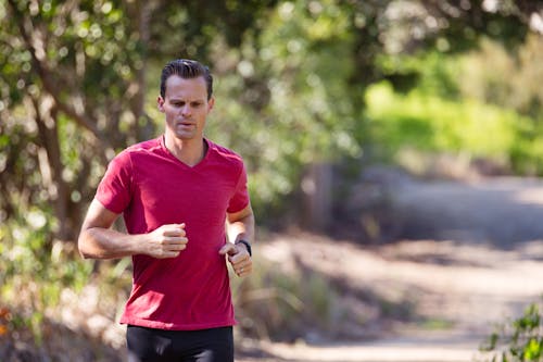 Free Man Running on Path Surrounded With Trees Stock Photo