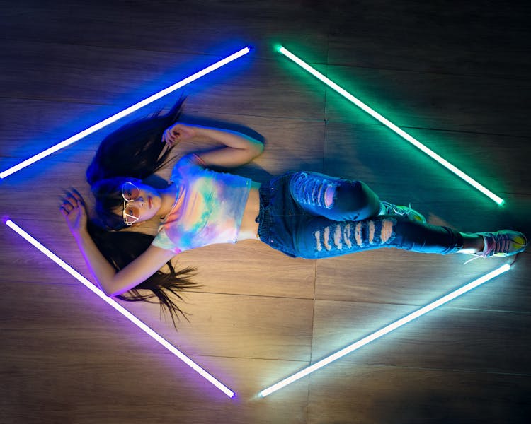 A Woman Lying Down On The Floor With Neon Lights