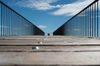 蔚蓝天空下，一条带有金属栏杆的现代木板路呈现低角度透视