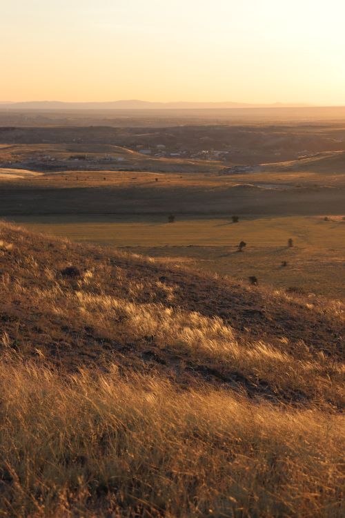 Free Capture the serene beauty of sunset over undulating fields and distant hills, highlighting natural tranquility. Stock Photo