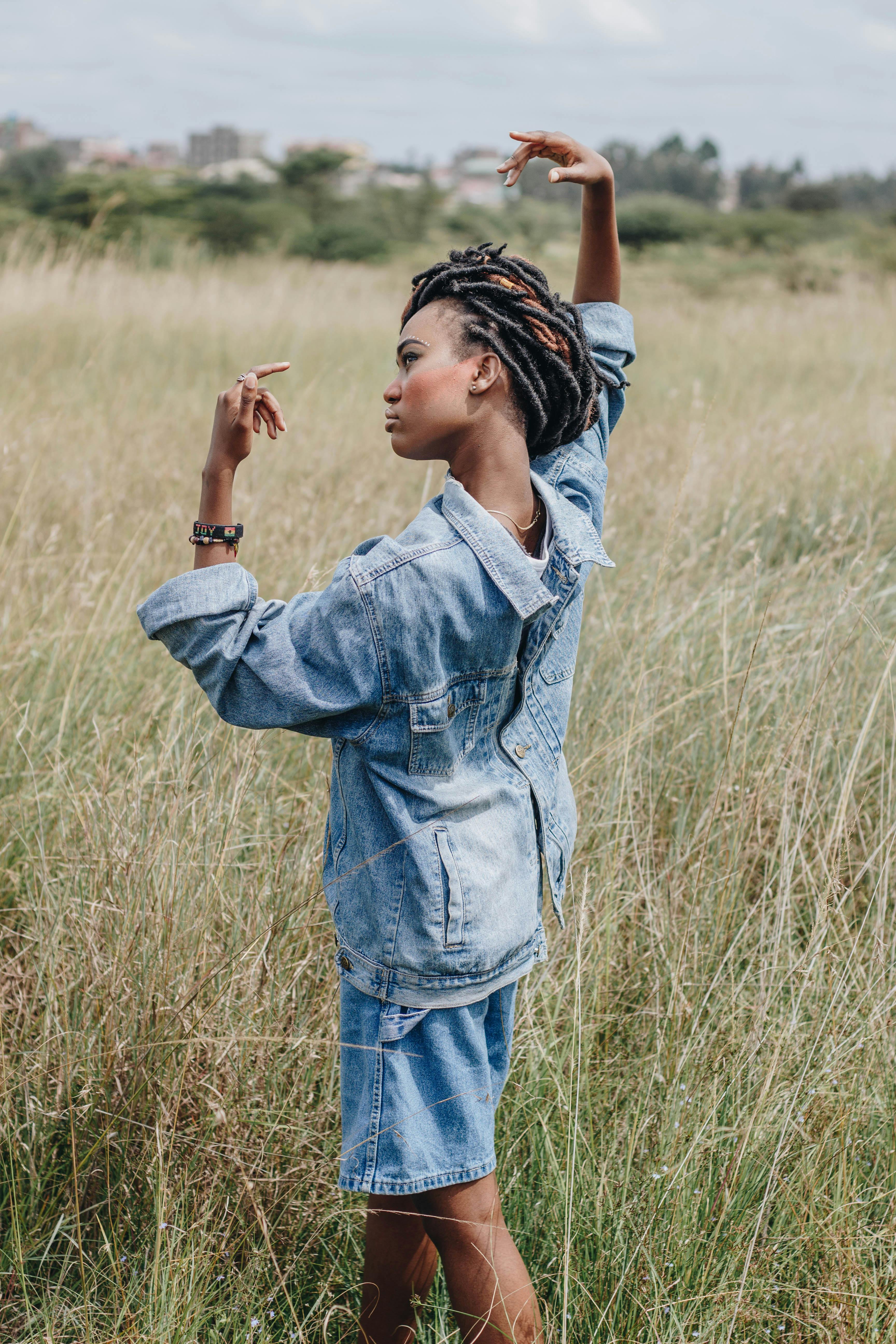 一位穿着牛仔夹克的年轻女子在草地上无忧无虑地跳舞