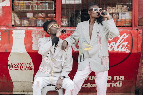 無料 キオスクの隣でコカ・コーラを飲む二人 写真素材