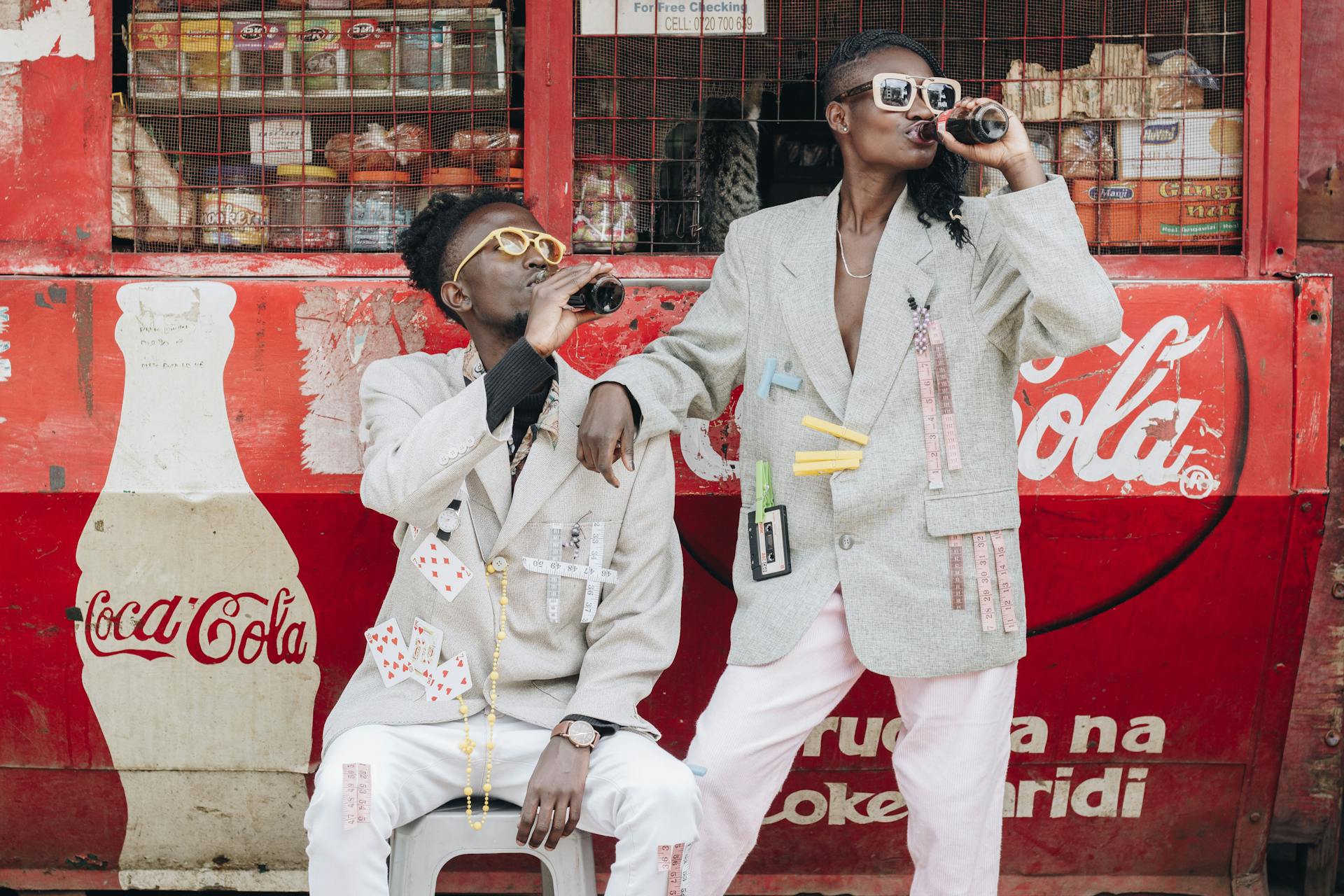 Two Person Drinking Coca-cola Next to a Kiosk