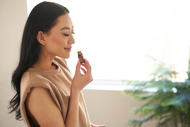 Woman In Beige Sleeveless Shirt Smelling An Aromatic Oil