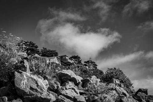 Grayscale Photo of a Rocky Mountain under the Cloudy Sky