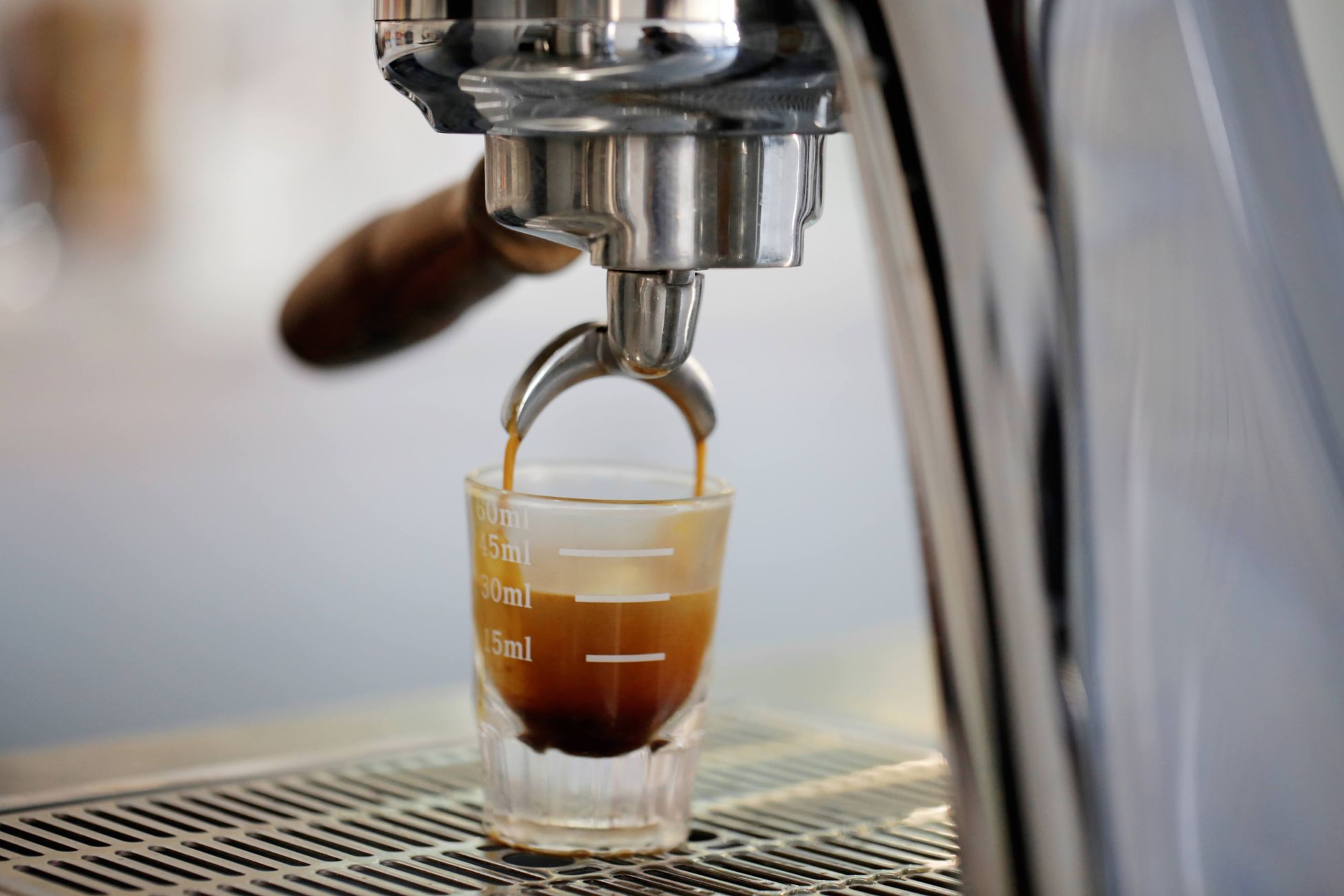 A close-up view of an espresso shot being brewed from a coffee machine into a glass cup.