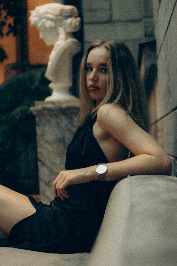 A Woman In A Halter Top Dress Sitting On A Couch