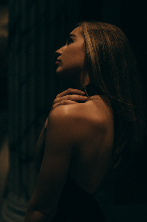 Free Elegant side-profile portrait of a woman in dim lighting with a dramatic and mysterious ambiance. Stock Photo