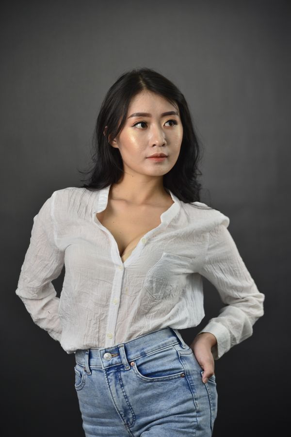 Model in a sheer white blouse on a dark studio backdrop, photo by Nhu Khue on Pexels