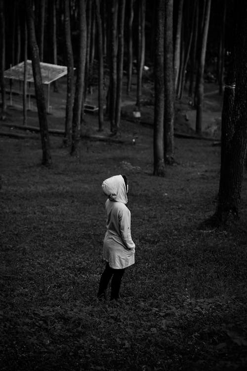 Monochrome Photo of a Person Standing Near Trees