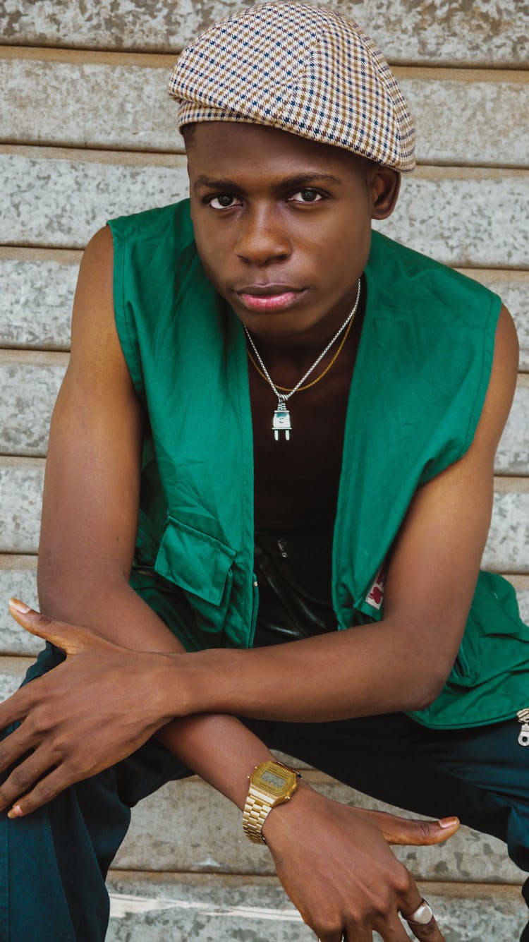 A Man Wearing Green Vest Sitting On Brown 