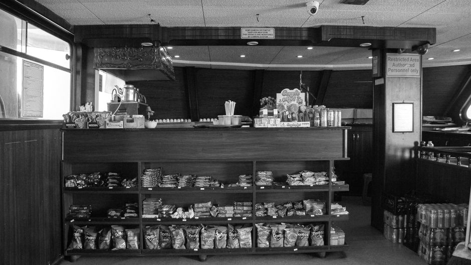 Convenience store clerk arranging traditional counter display stands with bulky fixtures