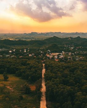 Drone shot of Vietnamese countryside with lush forests, rolling hills, and scenic sunset.