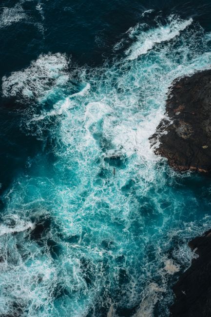 A stunning aerial view capturing the dramatic seacoast and turbulent sea waves of Faeröer.