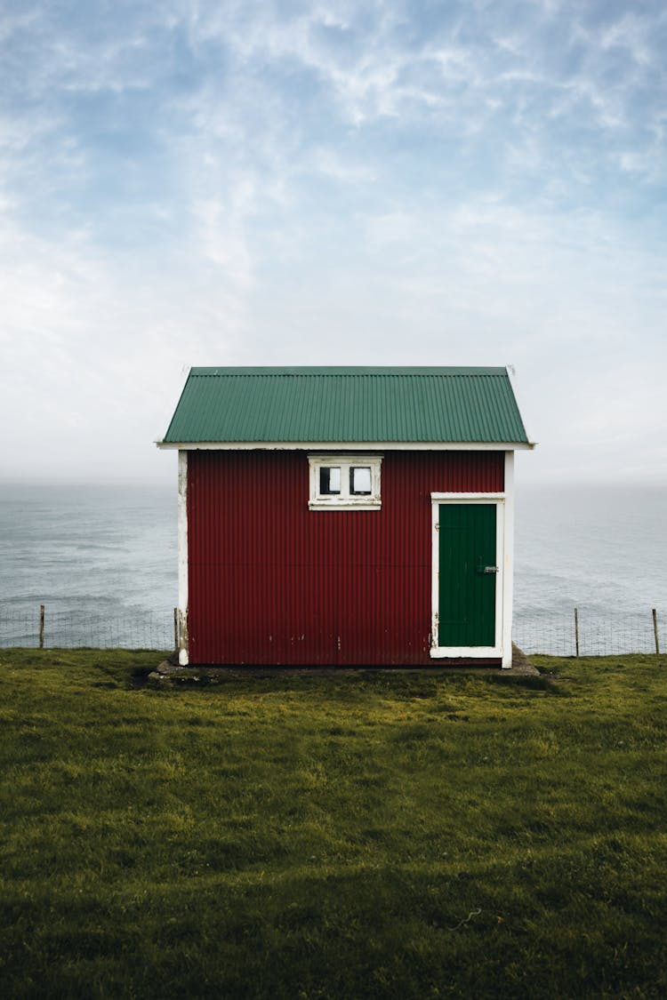 Small House Standing In Meadow By Sea