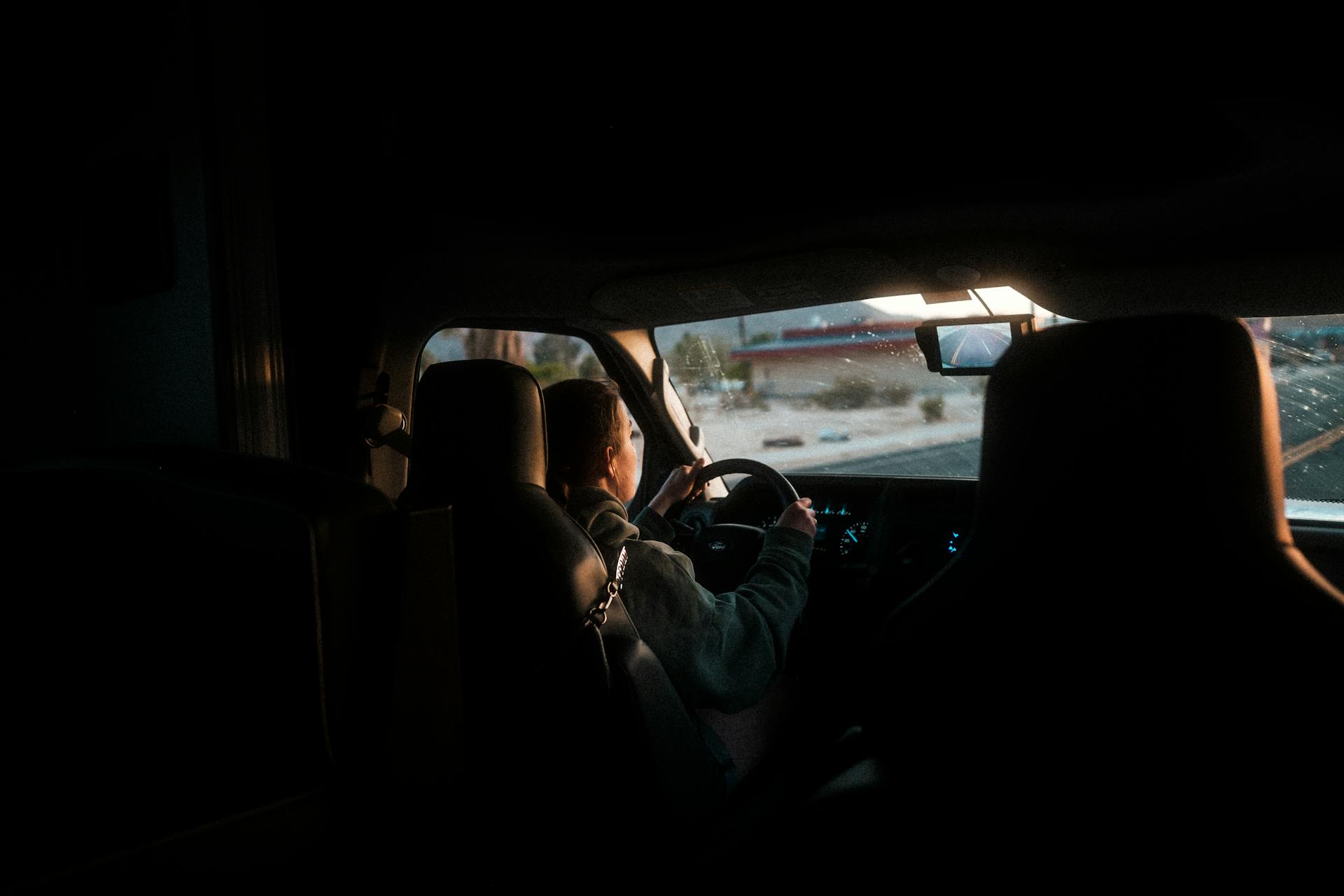 A woman driving a car through California at twilight, interior view.