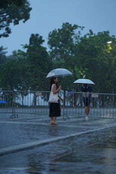 A woman walking with an umbrella during a rainy day, capturing mood and motion.