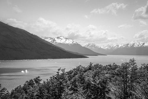 Grayscale Photo of Mountain Near Body of Water