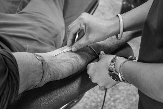 Detailed view of a blood donation procedure in progress, focusing on the needle insertion.