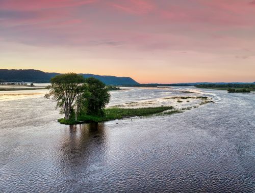 Free Aerial view of a tranquil river at sunset in Plainview, Minnesota with serene reflections and lush greenery. Stock Photo