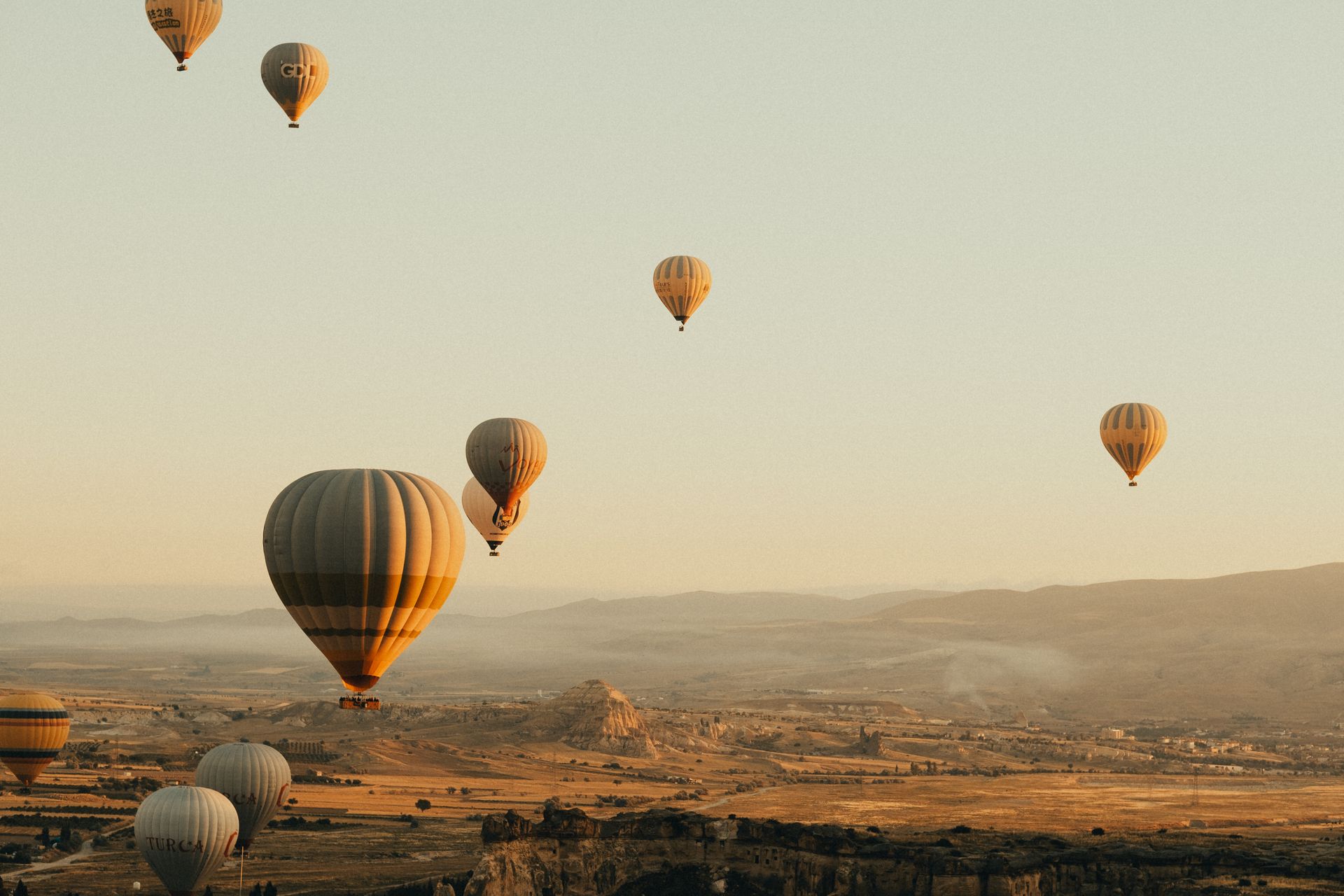 Scenic view of hot air balloons floating over Cappadocia's landscape during sunrise, capturing a ser