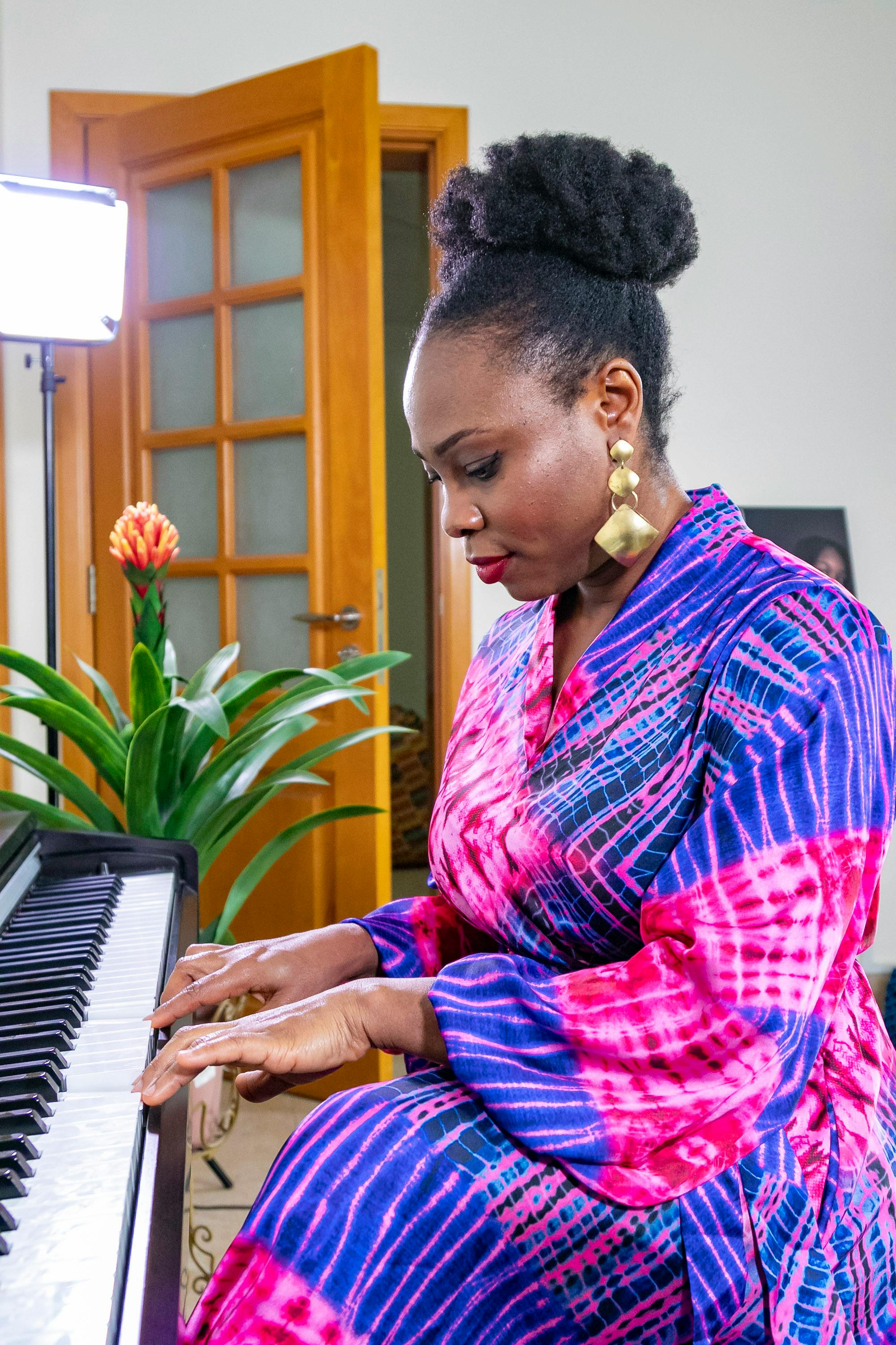 african woman wearing purple silk dress playing the piano