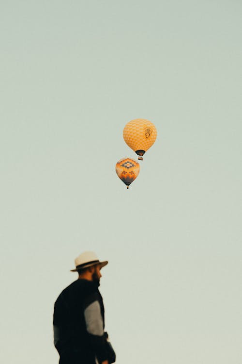 Hot Air Balloons Flying in Sky above Man 