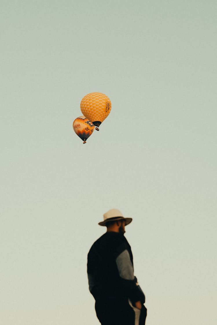 Hot Air Balloons Flying Above Man Head