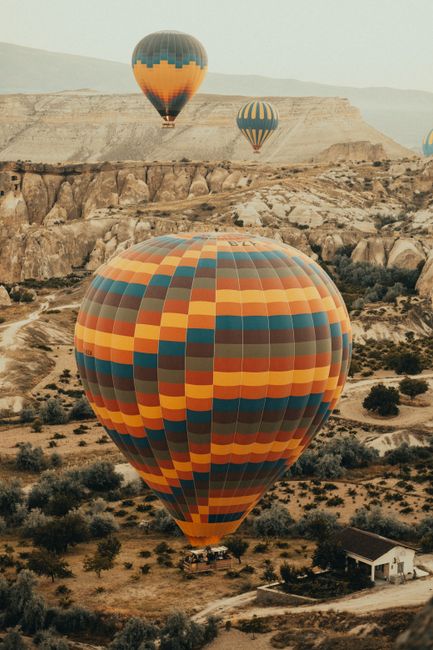 Vibrant hot air balloons soaring over Cappadocia's unique rock formations at sunrise.