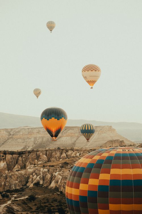 Free A picturesque view of colorful hot air balloons floating over the rocky landscapes of Cappadocia, Turkey. Stock Photo