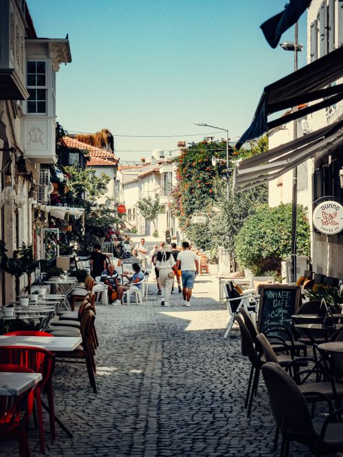 Free Picturesque cobblestone street with outdoor cafés and people enjoying a sunny day. Stock Photo