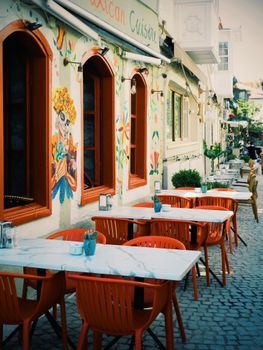 Vibrant outdoor cafe scene featuring colorful chairs and artistic murals on a sunny day.
