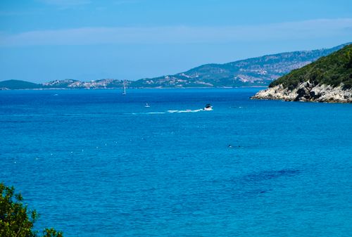 Free Majestic view of Perdika's vibrant blue sea with distant islands and a sailing boat. Stock Photo