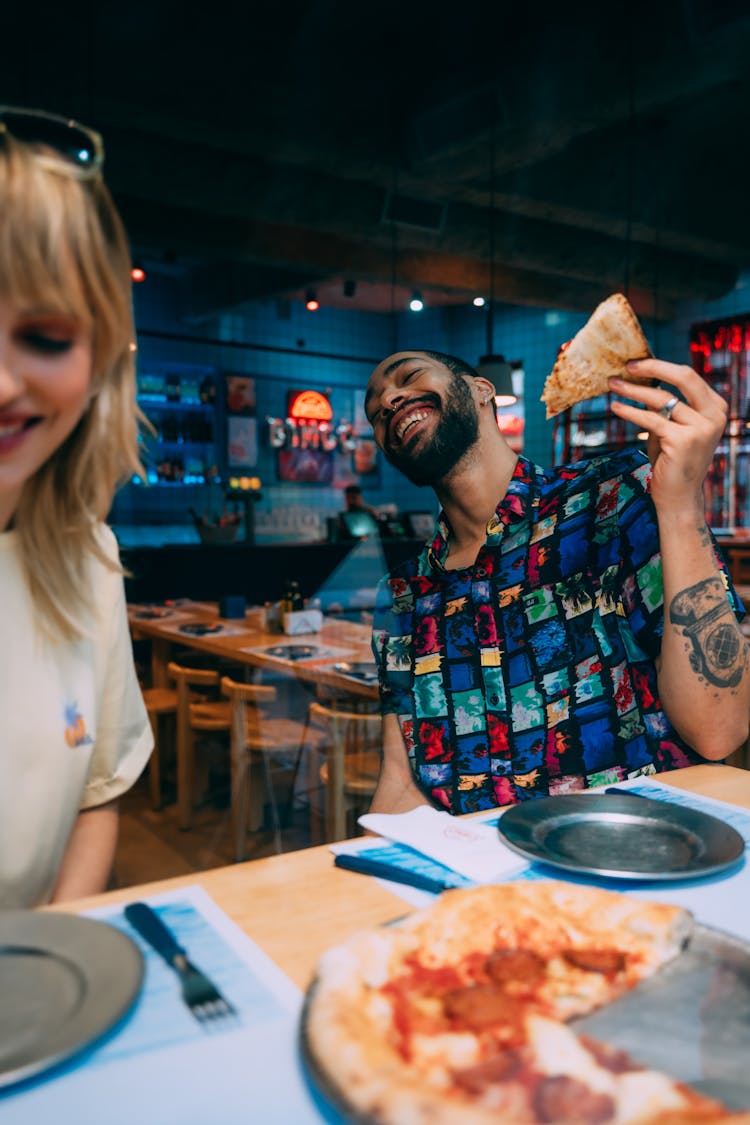 Couple Sitting In Bar And Eating Pizza