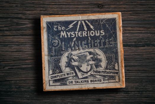 Antique mysterious planchette game board on rustic wooden surface.
