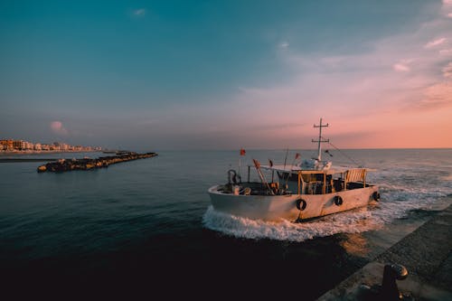 White Fishing Boat on Sea Under Blue Sky