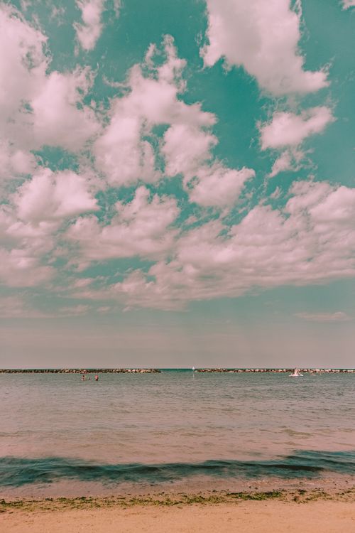 Free Peaceful beach with gentle waves and clouds in a serene setting. Stock Photo