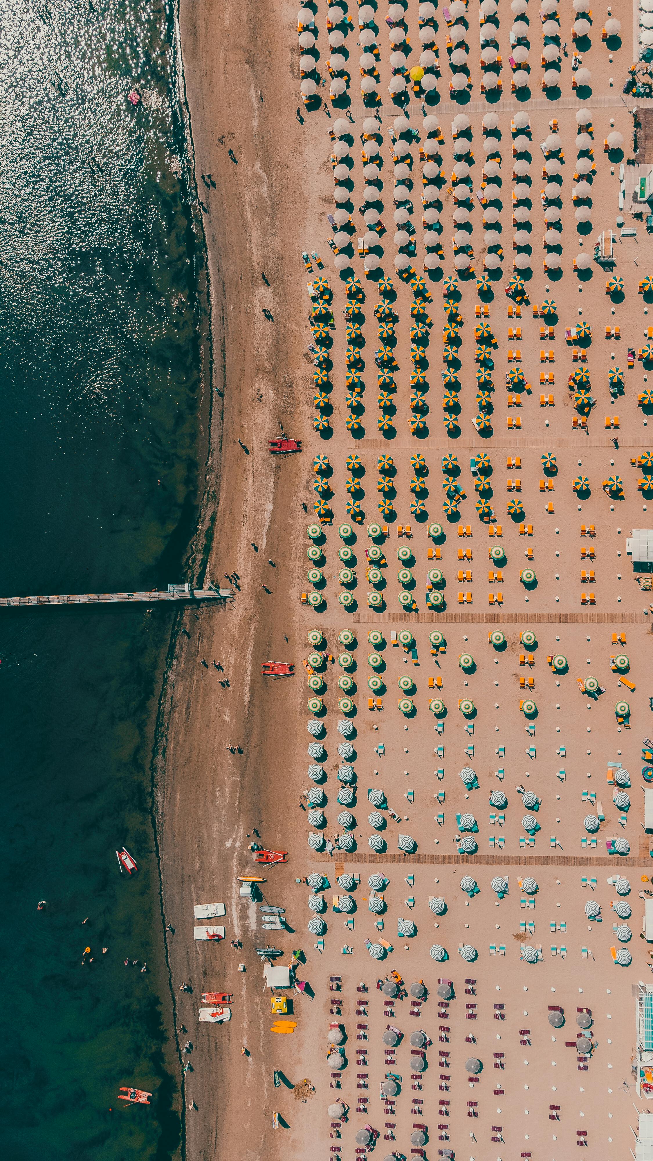 令人惊叹的鸟瞰图捕捉到夏季伊赫码头海岸线上色彩缤纷的海滩伞